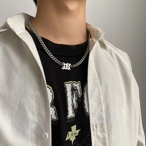 Close-up of silver Cuban link chain necklace with a Gothic letter D pendant on a model