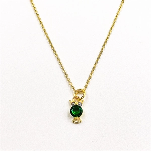 Detailed macro view of owl pendant with green gemstone and white zircon in gold finish