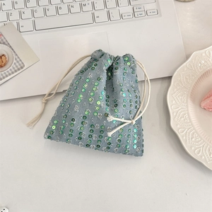 Macro shot of light blue denim drawstring pouch featuring vibrant green sequins