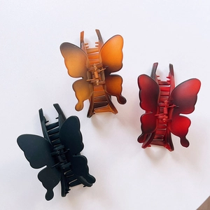 Detailed view of matte butterfly hair claws in black, amber, and burgundy resin colors
