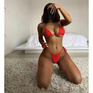 Detail of red halter neck triangle bikini top and side-tie bottoms on a soft carpet