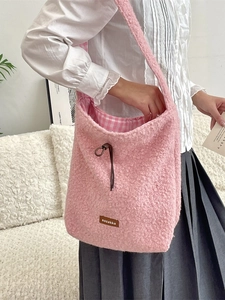 Pink fleece teddy shoulder bag with leather label and drawstring shown on a model