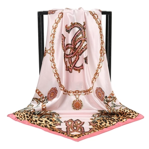 Pink satin leopard and gold chain print silk scarf draped on a black geometric frame