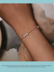 Close-up of S925 sterling silver dachshund and paw print charms on a delicate wrist chain