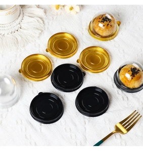 Macro detail of round gold and black plastic pastry trays with clear dome lids