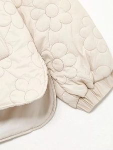 Detail of floral quilted jacket featuring elastic cuffs and curved hem in beige