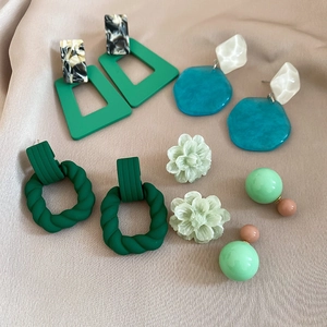 Detailed macro view of geometric acrylic drop earrings set in various green forest tones