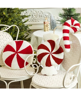 Close-up of candy cane and peppermint plush pillows on a chair with Christmas decor