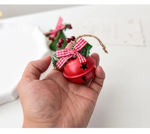 Macro shot of red metal Christmas bell with star cutouts and a plaid bow decoration
