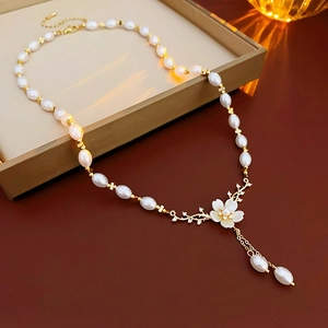 Détail d'un collier floral doré avec perles et cristaux sur un plateau à bijoux beige