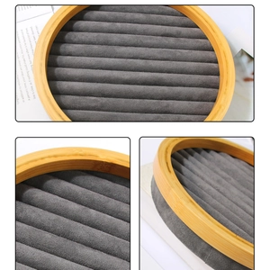 Macro view of round bamboo jewelry tray with dark grey velvet slots for rings