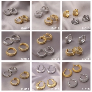 Macro view of assorted hoop earrings with zircon inlay on grey silk fabric texture