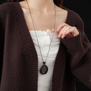 Close-up of a dark brown wooden water drop pendant necklace on a simple brown cord