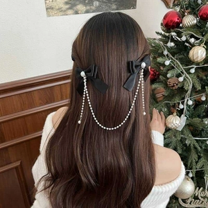 Detail of girl wearing black bows with pearl chains in a festive holiday setting