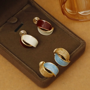 Detail of colorful enamel spiral clip-on earrings displayed in a velvet jewelry box