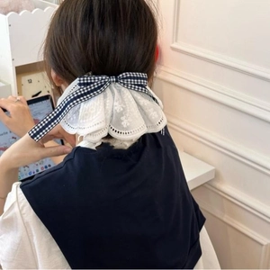 Detailed back view of a layered white lace hair clip with a blue plaid bow on a model