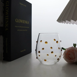 Detail view of transparent glass cup with amber polka dots and wavy tactile surface