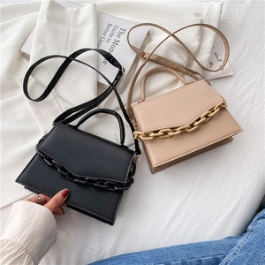 Minimalist chain flap handbags in black and beige displayed with fashion magazine