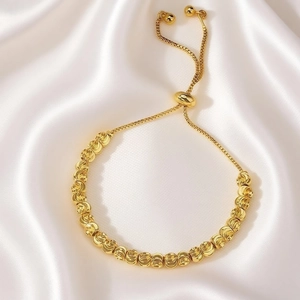Close-up of 18k gold bead bracelet with adjustable slider clasp on white silk fabric
