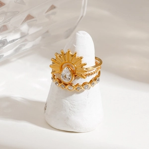 Macro shot of gold-plated three-piece stackable ring set with cubic zirconia on white stand
