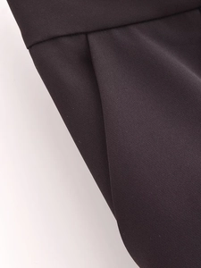 Detailed close-up of black high-waisted trousers showing twill fabric texture and side pocket