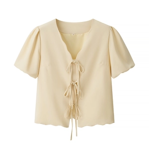 Detail of short sleeve V-neck blouse with bow ties and ruffle trim in light yellow