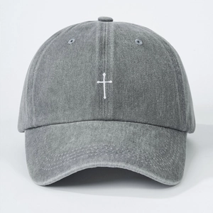 Close-up of a vintage grey washed denim baseball cap with white cross embroidery