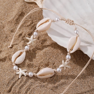 Detail of seashell anklet with starfish and white stones on a sandy beach shell