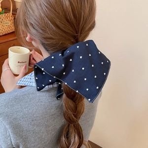 Détail d'un nœud à cheveux en tissu bleu marine avec motif cœur sur une tresse basse