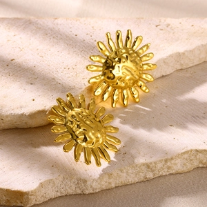Vintage gold sunflower stud earrings with hammered metal texture on a stone background