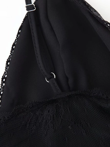 Detail of delicate black lace trim and thin strap with metal ring on V-neck dress