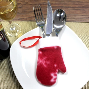 Red felt glove cutlery holder with snowflake pattern on white plate for Christmas dinner