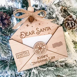 Detail of wooden envelope ornament with Dear Santa engraving hanging on a snowy tree