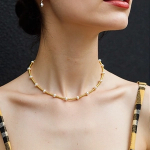 Macro detail of French style gold beaded necklace with elegant freshwater pearls for women