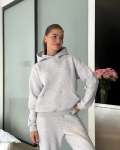 Detail of grey hooded tracksuit with kangaroo pocket and ribbed cuffs in a modern interior