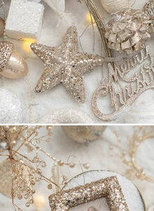 Close-up of golden stars, pine cones, and Merry Christmas ornaments on white snow