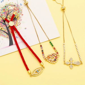 Nahaufnahme von Herz-Perle, buntem Kreuz und Evil Eye Charms auf drei schicken Armbändern