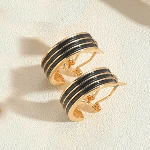 Macro shot of 14K gold-plated half-hoop earrings with elegant black enamel stripes