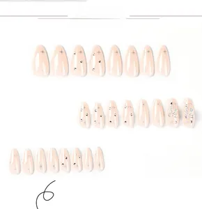 Detail of pink almond press-on nails with silver star patterns and 3D bow rhinestones