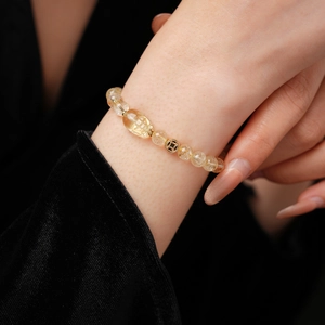 Macro shot of citrine beaded bracelet with golden wealth coin and pixiu charm