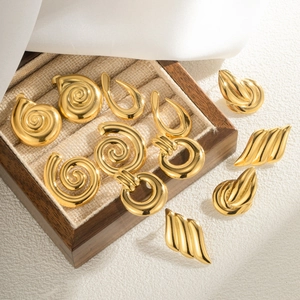 Golden geometric conch earrings set with spiral and ring designs in a wooden jewelry box