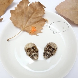 Brown skull ornaments on white tray with autumn leaves for Halloween DIY decor