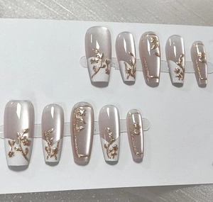 Detail van lange coffin press-on nagels met wit Frans ontwerp en goudfolie details