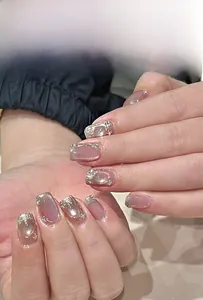 Detail von rosa Katzenaugen-Pressnägeln mit silbernem Glitzer und Perlen am Handgelenk