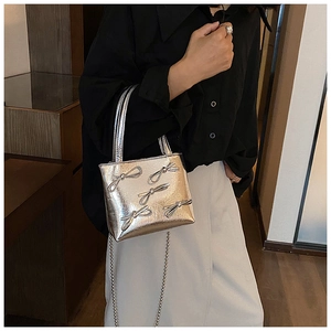 Silver metallic mini bag with ribbon bows and chain strap shown on a model