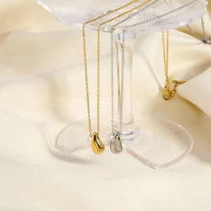 Detail of gold and silver teardrop pendants on glass rack with elegant silk background
