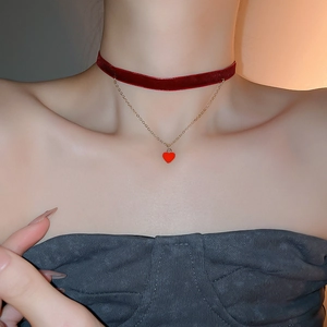 Detail of red velvet choker with gold chain and heart pendant on a model neck