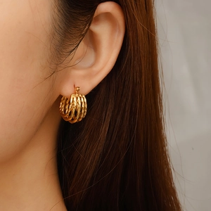 Women's 18K gold-plated multi-layer woven hoop earrings shown on a model's ear