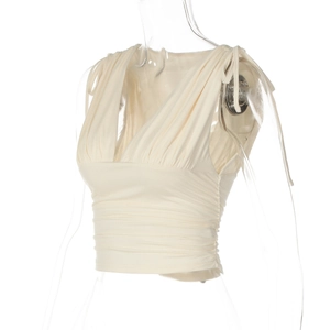 Dettaglio top corto color crema con scollo a V, increspature e lacci sulle spalle