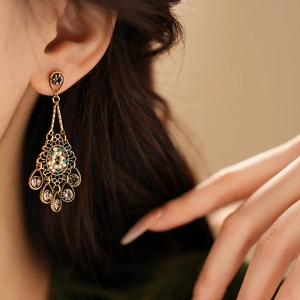 Close-up of vintage gold floral earrings with pearls and colorful gems on a model